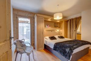 a bedroom with a bed and a chair and a window at Chalet des Oursons in Cohennoz
