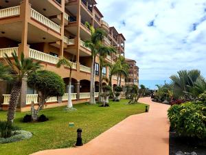 a resort building with palm trees and a walkway at El Nautico Apartment in San Miguel de Abona