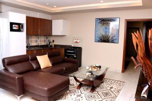 un soggiorno con divano marrone e tavolo di Montecito Apartments a Accra