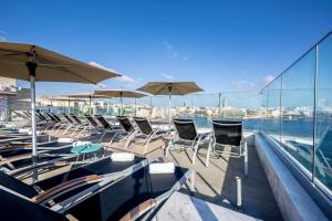 a group of chairs and tables and umbrellas on a balcony at Plaza Regency Hotels in Sliema