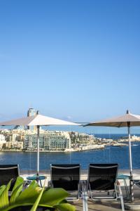 a group of chairs and umbrellas on a patio at Plaza Regency Hotels in Sliema
