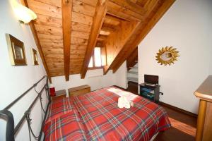 a bedroom with a bed in a room with wooden ceilings at Trilocale Alpinsun - Accoglienza per 5 persone in Sozzine