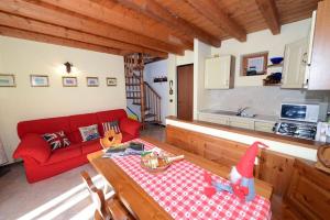 a living room with a red couch and a table at Trilocale Alpinsun - Accoglienza per 5 persone in Sozzine