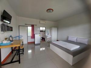 a bedroom with a bed and a table and a kitchen at Sailom Resort​ in Chom Thong
