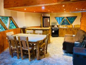 a kitchen and dining room with a table and chairs at Domos Hijos del Bosque in Coñaripe