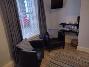 een woonkamer met 2 stoelen en een raam bij 29 Well Street B&B in Moffat