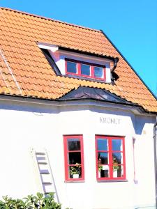a white house with red windows and a orange roof at Åberg12 in Höör
