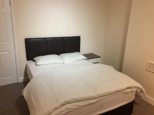 a bedroom with a large white bed with a black headboard at Duncan House in Leicester