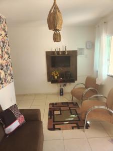 a living room with a couch and chairs and a tv at Casa de praia in Arembepe