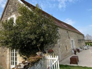 un antiguo edificio de piedra con una valla blanca y un árbol en LA CHARMILLE Jolie maison de campagne 14 personnes piscine calme, en Entrains-sur-Nohain