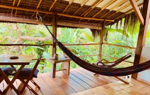 a hammock in a room with a table and a table and a tablektop at CASA AITI, ex-Casa da Cris e Paulo in Ilha de Boipeba