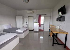Habitación con 2 camas, mesa y nevera. en Sailom Resort​, en Chom Thong