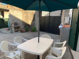un tavolo bianco con sedie e ombrellone di Casa Ziu Juanne a Orosei