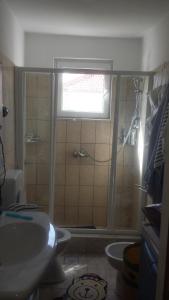 een badkamer met een wastafel en een douche met een raam bij Studio apartman in Jezera