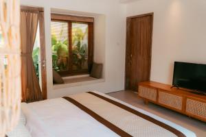 a bedroom with a bed and a flat screen tv at Sanjula Uluwatu in Uluwatu