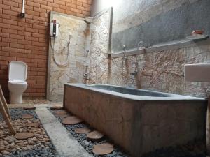 a bathroom with a bath tub and a toilet at Sandalwood Cottage in Udawalawe