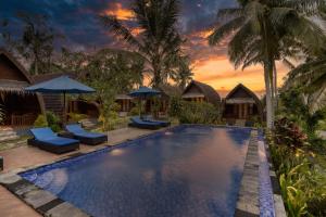 una piscina con sedie e ombrelloni in un resort di Kelingking Tatakan Bungalow a Nusa Penida