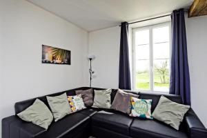 un sofá de cuero negro en una sala de estar con ventana en LA MARSEILLAISE 15 PERS PISCINE, en Étais-la-Sauvin