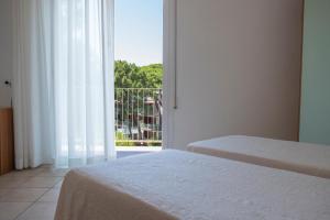 a bedroom with two beds and a large window at Hotel Orsa Maggiore in Milano Marittima