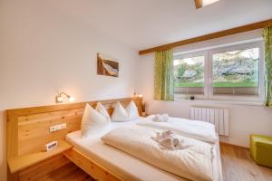 a bedroom with a bed with white sheets and a window at Haus Ottilia - Top 5 in Neukirchen am Großvenediger