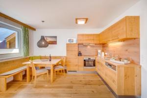 cocina con armarios de madera, mesa y comedor en Haus Ottilia - Top 5, en Neukirchen am Großvenediger