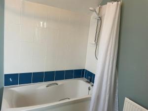 a bath tub with a white shower curtain in a bathroom at Spring View in Little Malvern