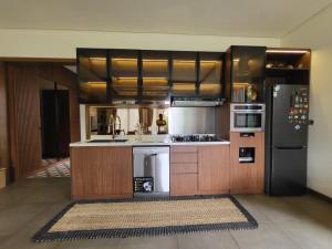 a kitchen with wooden cabinets and a black refrigerator at Villa Vimala Hills Semeru in Bogor
