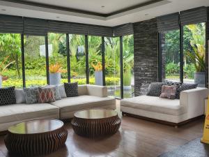 a living room with couches and tables and windows at Villa Vimala Hills Semeru in Bogor