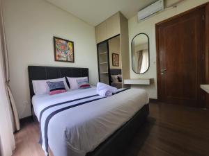 - une chambre avec un grand lit et un grand miroir dans l'établissement Villa Vimala Hills Semeru, à Bogor