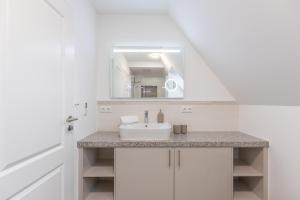 a white bathroom with a sink and a mirror at Getidenhus Sünn in Sankt Peter-Ording