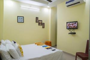 Schlafzimmer mit einem Bett und einem TV an der Wand in der Unterkunft Hotel Yellow Bells in Hyderabad