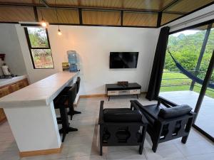 a kitchen with a bar with black chairs and a tv at Pacheco Tours Rainforest Cabins in Drake