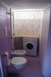 Fioletowa łazienka z toaletą i pralką w obiekcie Luan House w mieście San Giorgio a Cremano