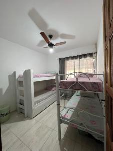 Pokój z 2 łóżkami piętrowymi i wentylatorem sufitowym w obiekcie Nosso Repouso Saquarema - Casa inteira com Piscina,churrasqueira privativos, Wi-fi,900m da praia, Tv-Smart. w mieście Saquarema