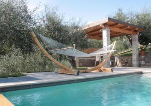 a hammock and a pergola next to a swimming pool at La Sassaiola by Nicola Real Estate in Corsanico-Bargecchia