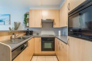 a kitchen with wooden cabinets and a sink and a microwave at Gaugain E 601 in Nieuwpoort +6 photos