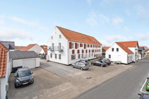 a street with cars parked in front of a white building at Completely Renovated Holiday Apartments in Løkken