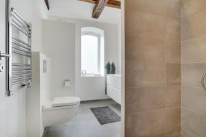 a white bathroom with a toilet and a sink at Completely Renovated Holiday Apartments in Løkken +10 photos