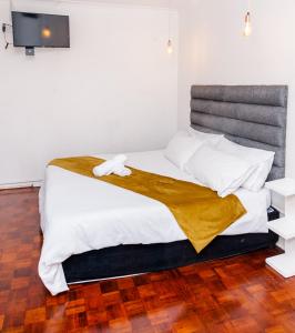 een slaapkamer met een groot bed en een houten vloer bij Nkosazana Guest House in Durban