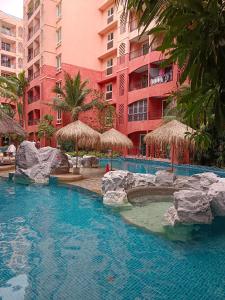 a swimming pool in front of a large building at Seven Seas Condo Resort Beautiful Location in Jomtien Beach