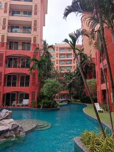 a swimming pool in front of a building with palm trees at Seven Seas Condo Resort Beautiful Location in Jomtien Beach