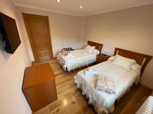 a small room with two beds and a television at La Casona El Carrascal in La Gandara