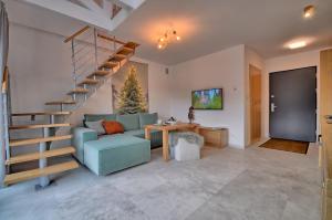 een woonkamer met een trap, een bank en een tafel bij Apartament Pistacjowy in Szczyrk