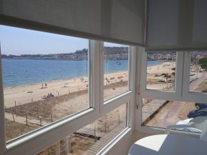 a view of a beach from a room with windows at Hotel Playa in Cangas de Morrazo