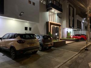 2 voitures garées sur un parking en face d'un immeuble dans l'établissement Casa Esmeralda Hotel Boutique, à Cali