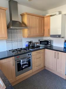 a kitchen with wooden cabinets and a stove top oven at M&J Apartment in Blackpool
