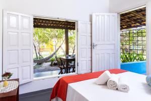 a bedroom with a bed and a view of a patio at Pousada Vila Rosa - Caraiva in Caraíva