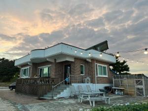 a house with a patio and a table and chairs at Gangneung Mediterranean Pension in Gangneung