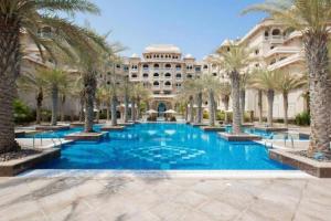 una grande piscina con palme di fronte a un edificio di Luxury 1Bedroom on Private Beach Residence at Palm a Dubai