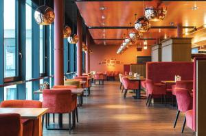 un ristorante con sedie rosse, tavoli e finestre di aja Grömitz a Grömitz